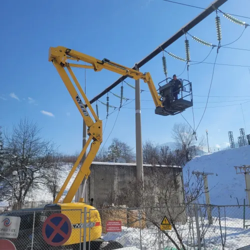 Nacelă hidraulică ridicată lângă linii electrice, pentru lucrări la înălțime.