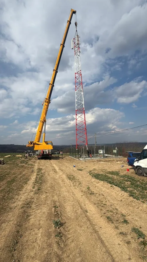 Automacara cu braț extins vertical, lângă linii de înaltă tensiune.