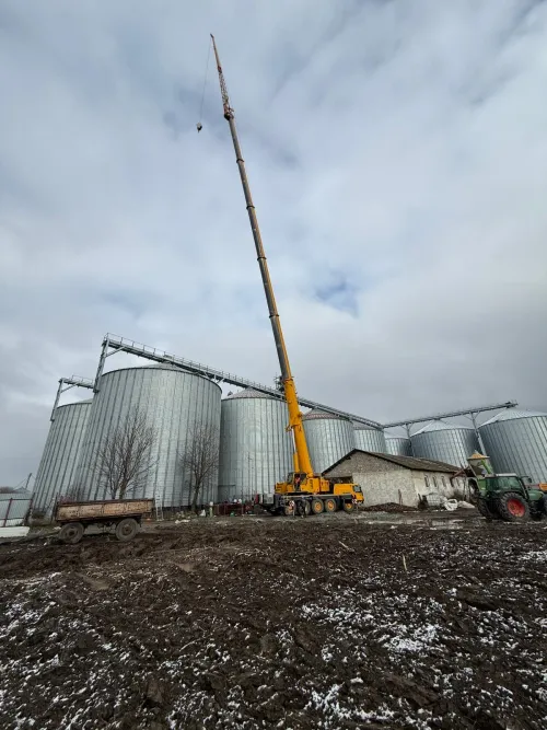 Macara mobilă lângă un complex de silozuri de cereale.