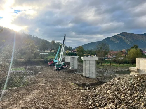 Automacara deplasată pe un drum de munte, cu peisaj deluros în fundal.