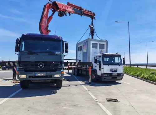 Automacara lucrând la structura metalică a unei clădiri parcare, cu un muncitor la înălțime.