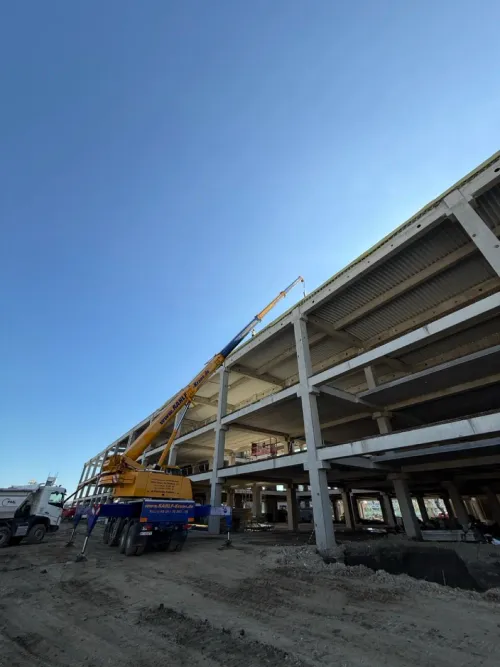 Automacara ridicând materiale la structura de beton a unei clădiri, dimineața.