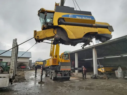 Automacara ridicând o combină agricolă, într-un atelier.