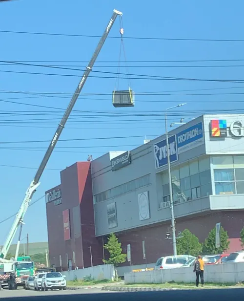 Automacara ridicând o unitate tehnică pe acoperișul unui centru comercial.