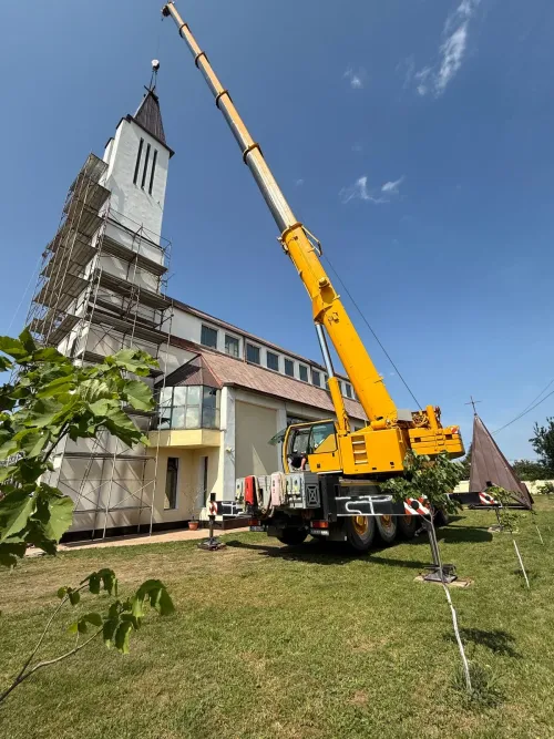 Automacara ridicând materiale la turnul unei biserici aflate în renovare.