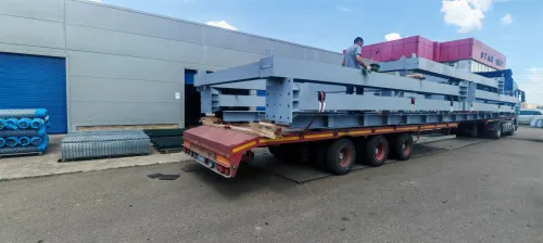 Transport agabaritic de grinzi metalice, cu însemnul "Convoi exceptionnel", pe platformă cu trailer.